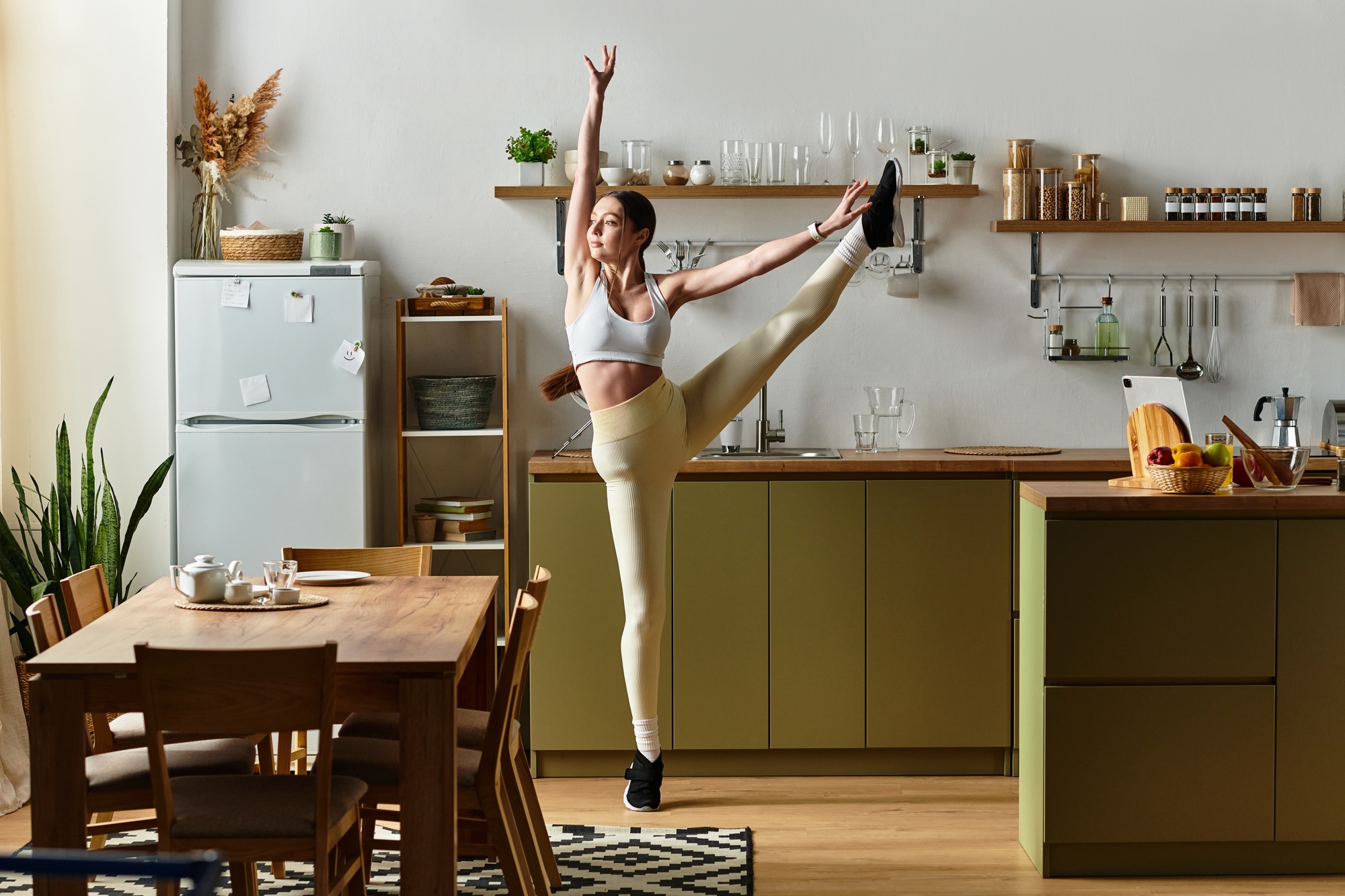 Dancing with joy in a modern kitchen while wearing leggings and a sports bra