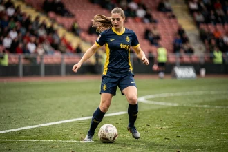 Joueuse de football féminin en action lors d'un match de Serie A italienne, dribblant le ballon sur la pelouse d'un stade